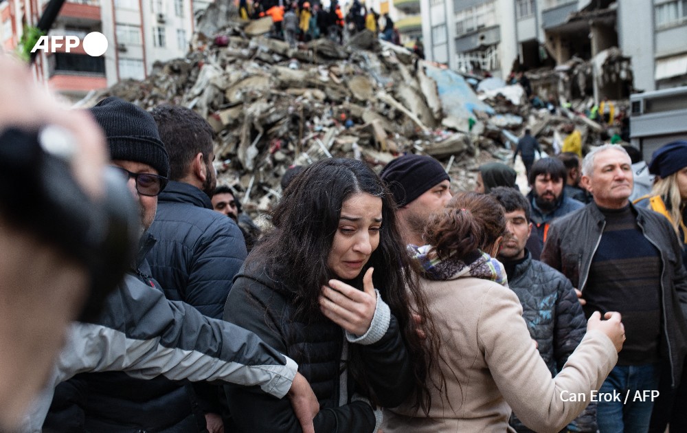 A woman reacts as rescuers search for survivors through the rubble of collapsed buildings in Adana after an earthquake struck Turkey. 